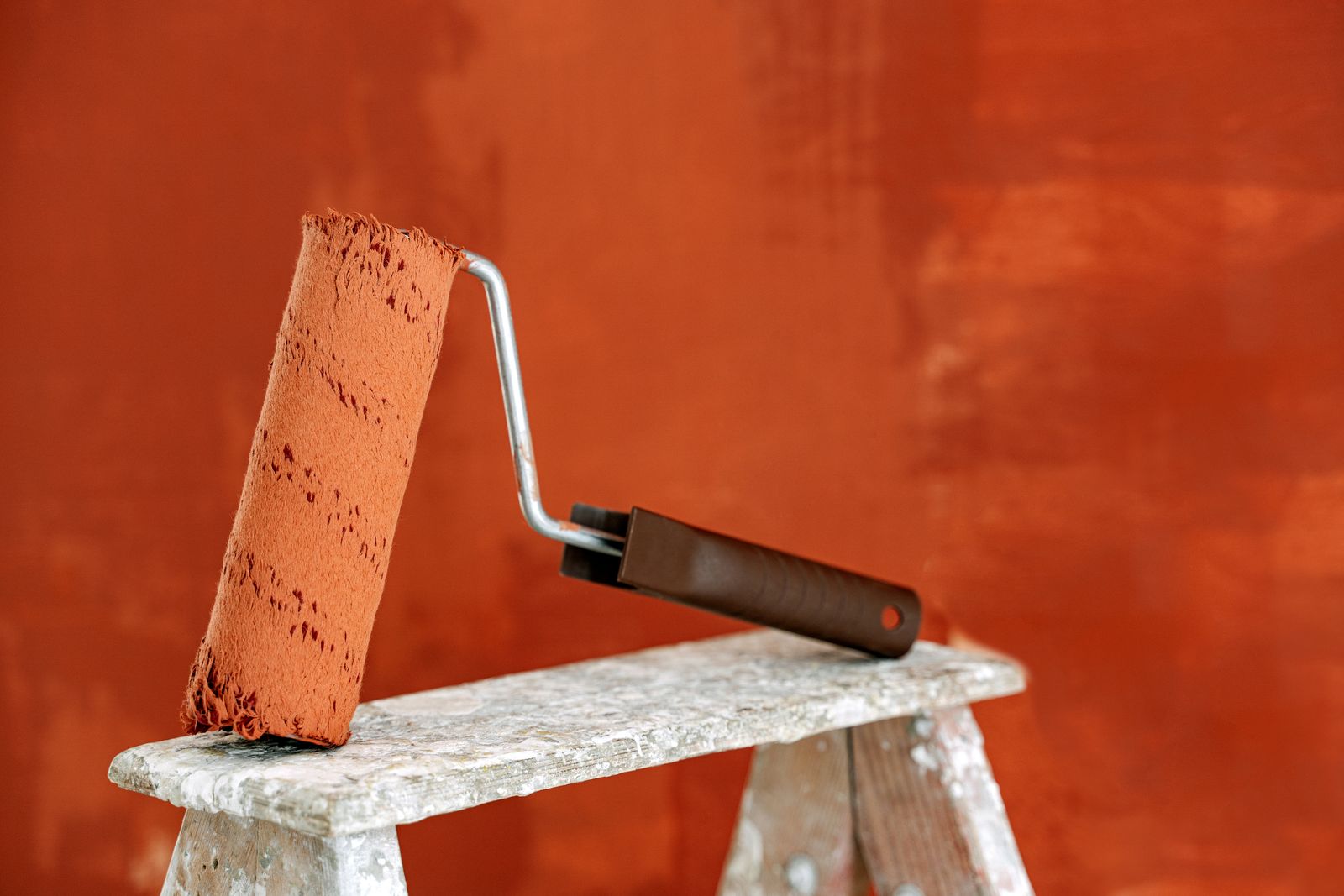 Paint roller beside a freshly painted terracotta wall